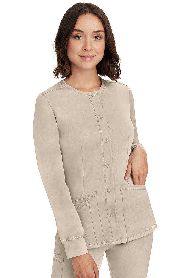 A young female RN wearing an HH-Works Women's Megan Snap Front Scrub Jacket in Khaki featuring front princess seaming to ensure a flattering fit.