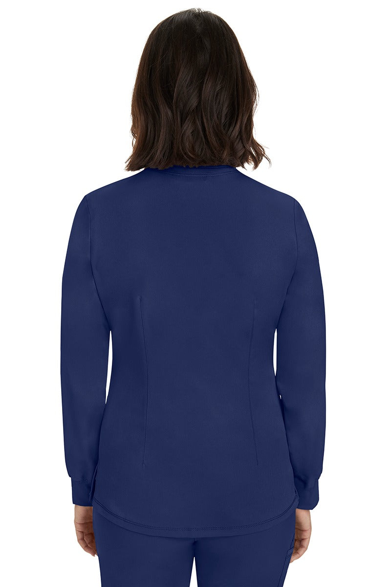 A young female Home Care Registered Nurse wearing an HH-Works Women's Megan Snap Front Scrub Jacket in Navy featuring a medium center back length of 25.5".