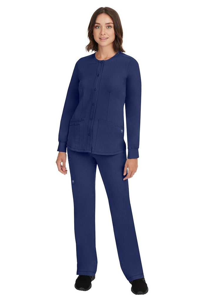 A young female Home Care Registered Nurse wearing an HH-Works Women's Megan Snap Front Scrub Jacket in Navy featuring yoga knit cuffs to ensure a flattering and comfortable fit.