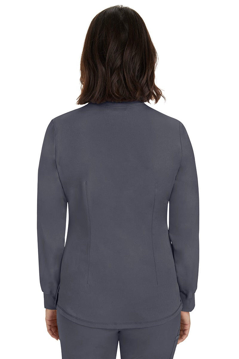 A young female Home Care Registered Nurse wearing an HH-Works Women's Megan Snap Front Scrub Jacket in Pewter featuring a medium center back length of 25.5".