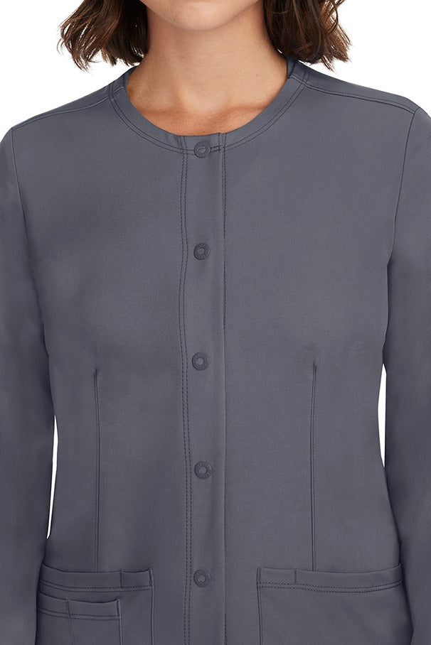 A female LPN wearing a Women's Megan Snap Front Scrub Jacket from HH Works in Pewter featuring a snap-up button front closure.