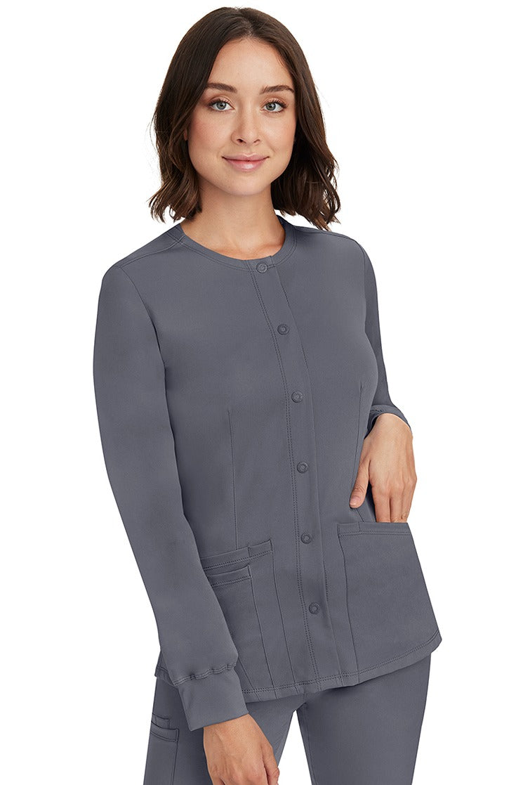 A young lady RN wearing an HH-Works Women's Megan Snap Front Scrub Jacket in Pewter featuring front princess seaming to ensure a flattering fit.