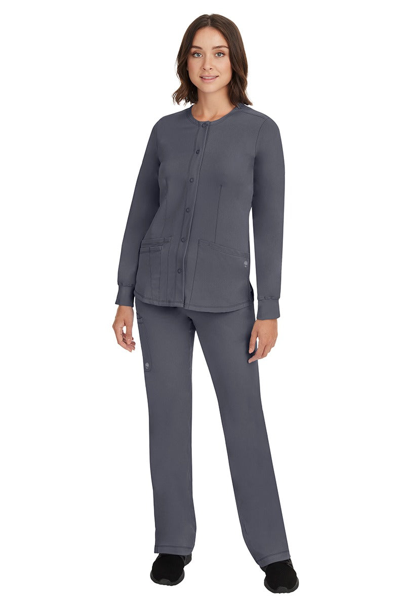 A young female Home Care Registered Nurse wearing an HH-Works Women's Megan Snap Front Scrub Jacket in Pewter featuring yoga knit cuffs to ensure a flattering and comfortable fit.