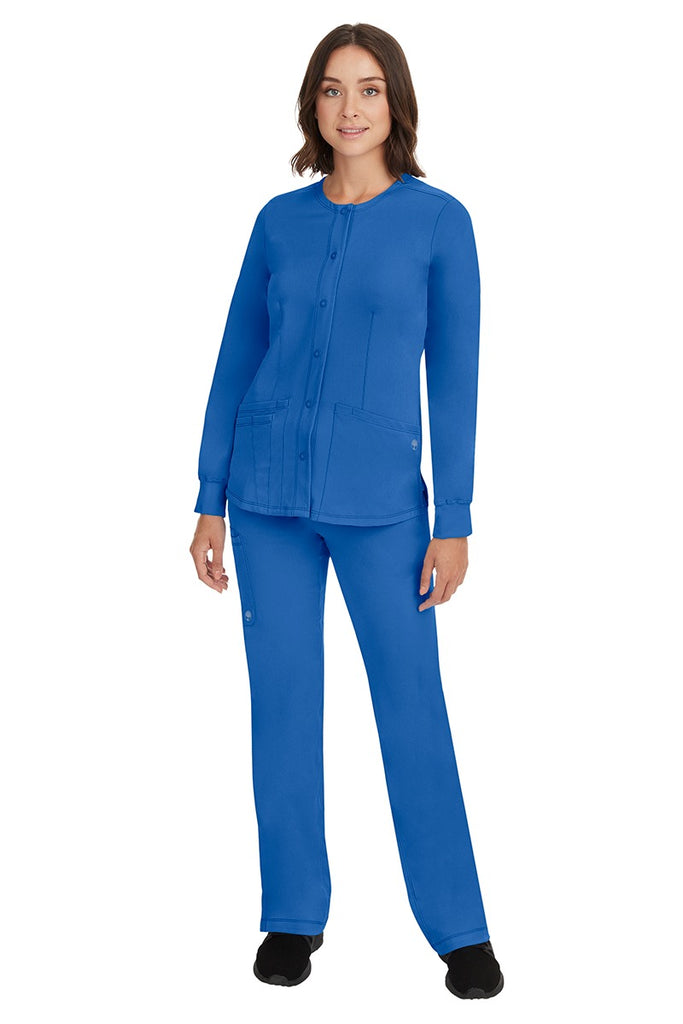 A young female Home Care Registered Nurse wearing an HH-Works Women's Megan Snap Front Scrub Jacket in Royal featuring yoga knit cuffs to ensure a flattering and comfortable fit.