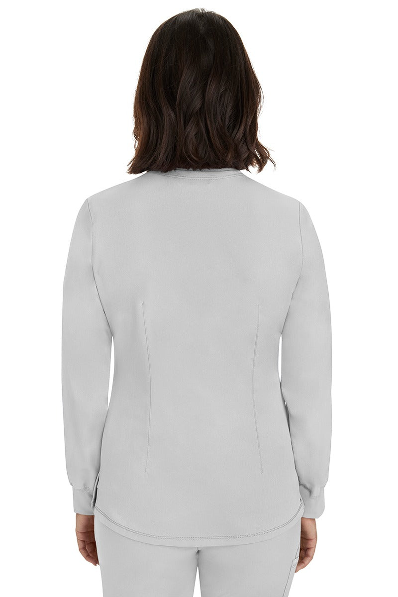 A young female Home Care Registered Nurse wearing an HH-Works Women's Megan Snap Front Scrub Jacket in White featuring a medium center back length of 25.5".