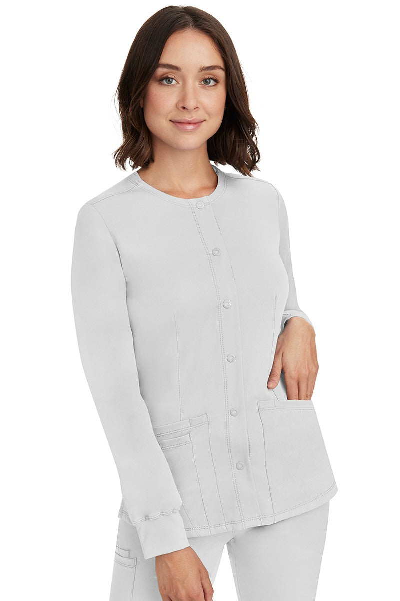 A young lady RN wearing an HH-Works Women's Megan Snap Front Scrub Jacket in White featuring front princess seaming to ensure a flattering fit.