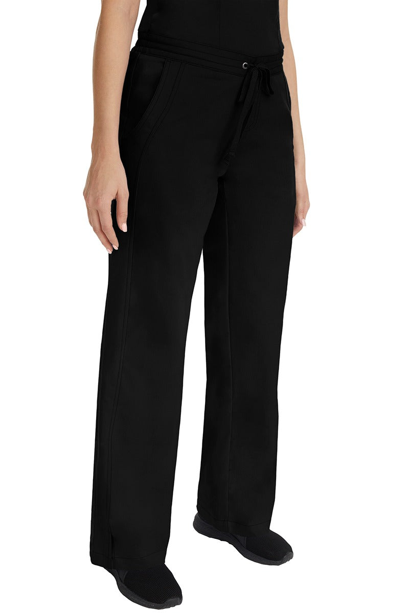 A young female RN wearing the Purple Label Women's Taylor Drawstring Scrub Pant in Black featuring side slits at the ankle for easy slip-on or removal.