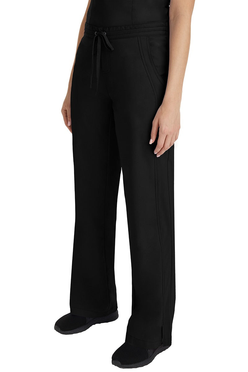 A young Home Care Registered Nurse wearing a Purple Label Women's Taylor Drawstring Scrub Pant in Black featuring front wrap seaming detail throughout.