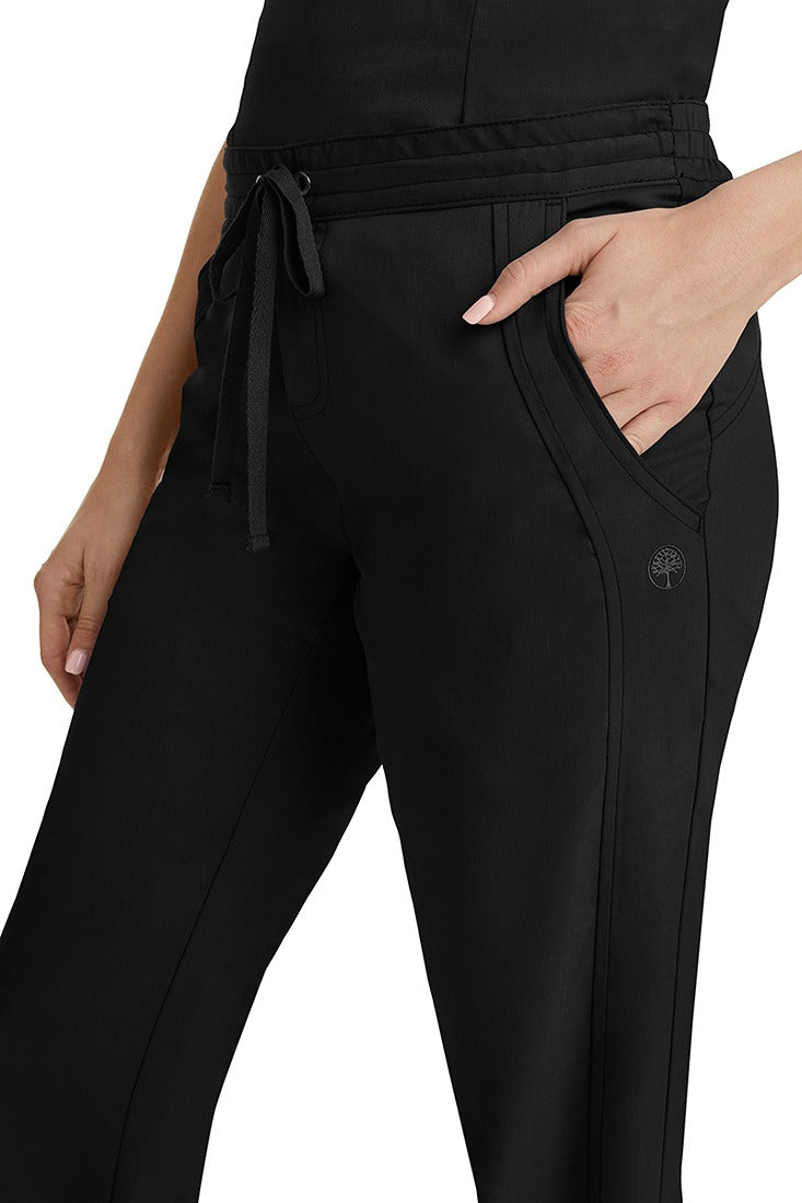 A young woman wearing a pair of Purple Label Women's Taylor Drawstring Scrub Pants from Healing Hands in Black. Perfect for Healthcare Professionals working in Hospitals, Doctors offices, Dental Groups & Veterinary offices!