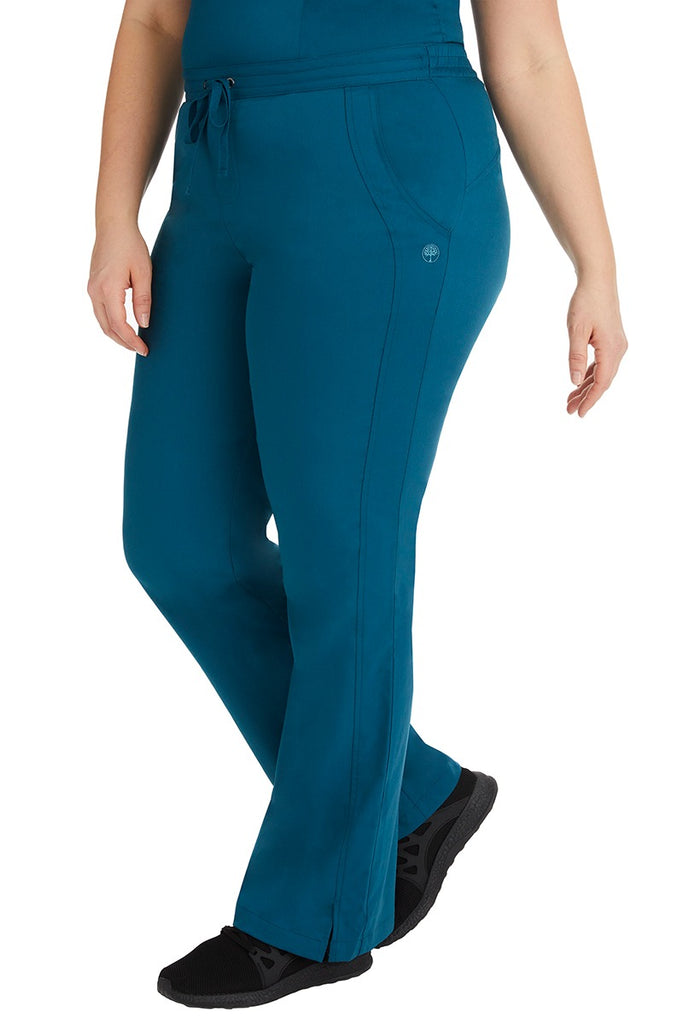 A young Home Care Registered Nurse wearing a Purple Label Women's Taylor Drawstring Scrub Pant in Caribbean featuring front wrap seaming detail throughout.