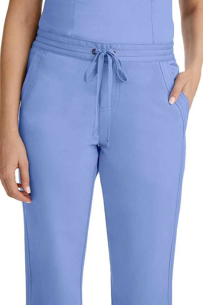A female healthcare professional wearing a Purple Label Women's Taylor Drawstring Scrub Pant in Ceil featuring triple needle stitching throughout.