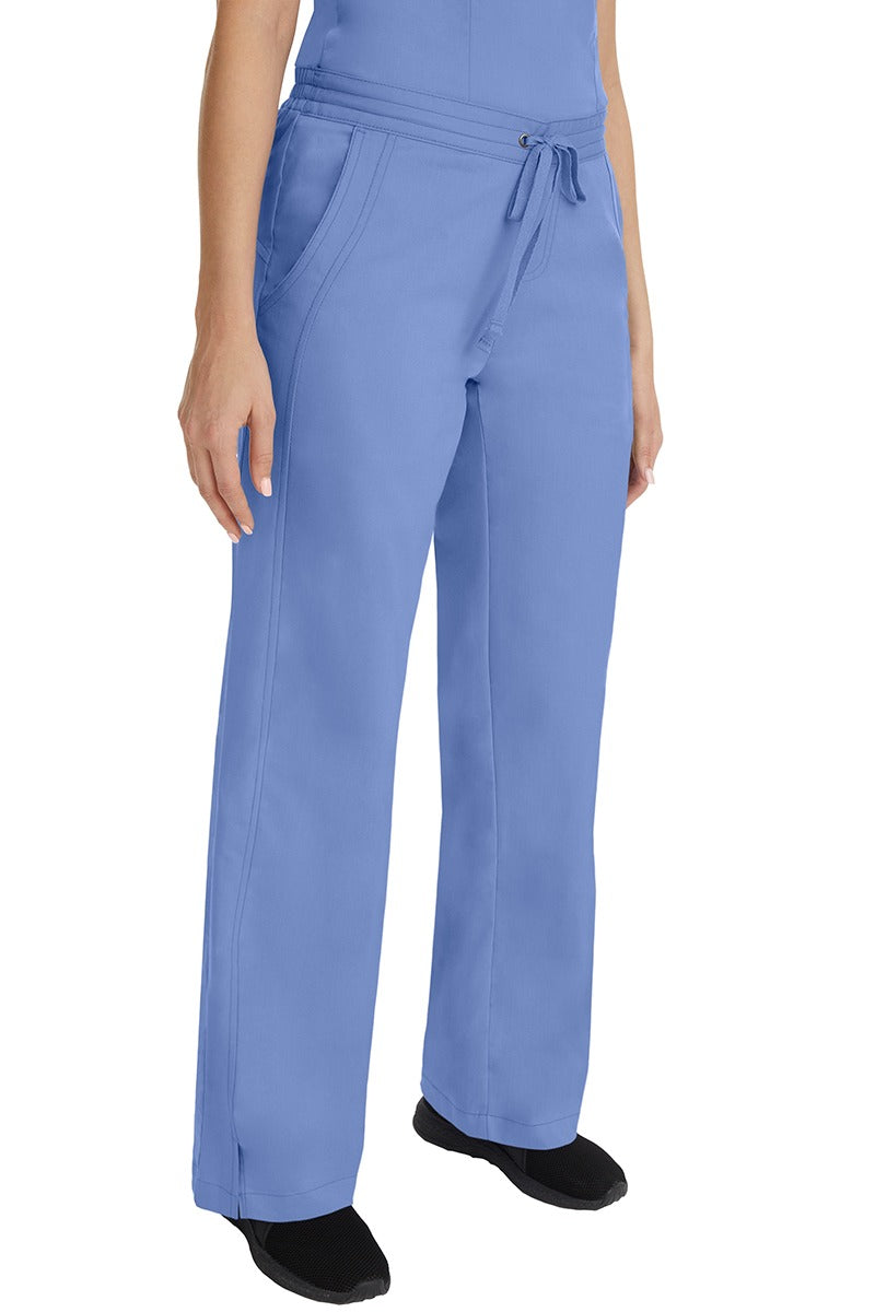 A young female RN wearing the Purple Label Women's Taylor Drawstring Scrub Pant in Ceil featuring side slits at the ankle for easy slip-on or removal.