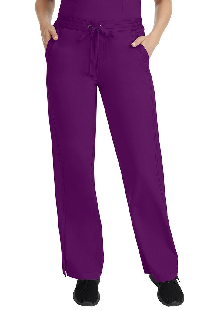 A female LPN wearing a pair of Purple Label Women's Taylor Drawstring Scrub Pants from Healing Hands in Eggplant featuring a front drawstring waist.