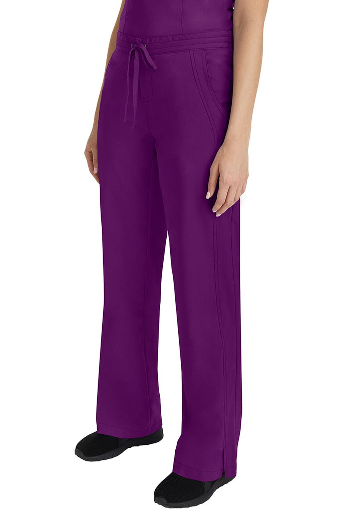A young Home Care Registered Nurse wearing a Purple Label Women's Taylor Drawstring Scrub Pant in Eggplant featuring front wrap seaming detail throughout.