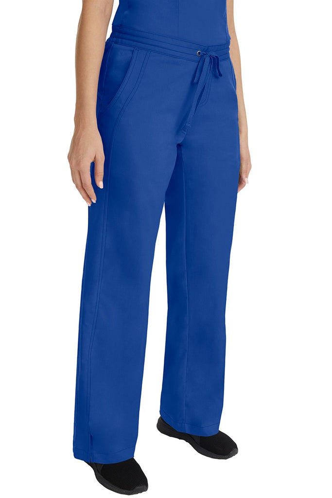 A young female RN wearing the Purple Label Women's Taylor Drawstring Scrub Pant in Galaxy Blue featuring side slits at the ankle for easy slip-on or removal.