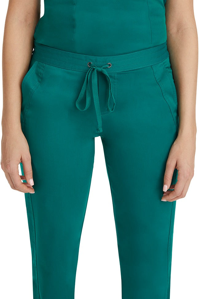 A female healthcare professional wearing a Purple Label Women's Taylor Drawstring Scrub Pant in Hunter Green featuring triple needle stitching throughout.