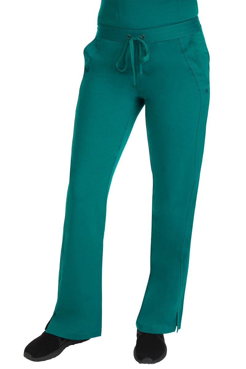 A young female RN wearing the Purple Label Women's Taylor Drawstring Scrub Pant in Hunter Green featuring side slits at the ankle for easy slip-on or removal.