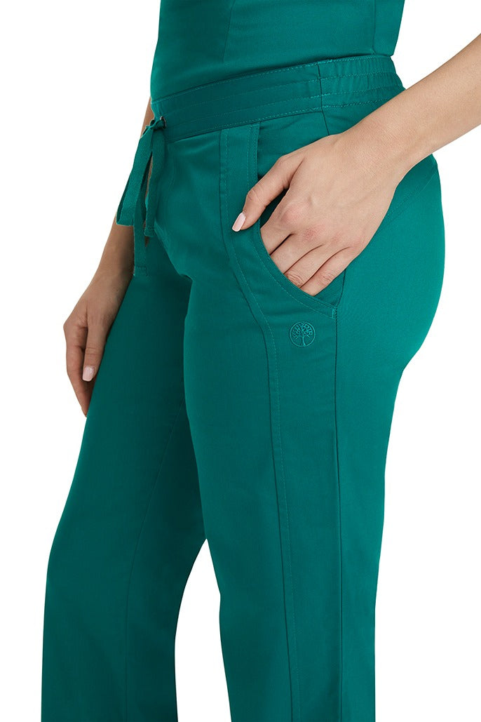 A young woman wearing a pair of Purple Label Women's Taylor Drawstring Scrub Pants from Healing Hands in Hunter Green. Perfect for Healthcare Professionals working in Hospitals, Doctors offices, Dental Groups & Veterinary offices!