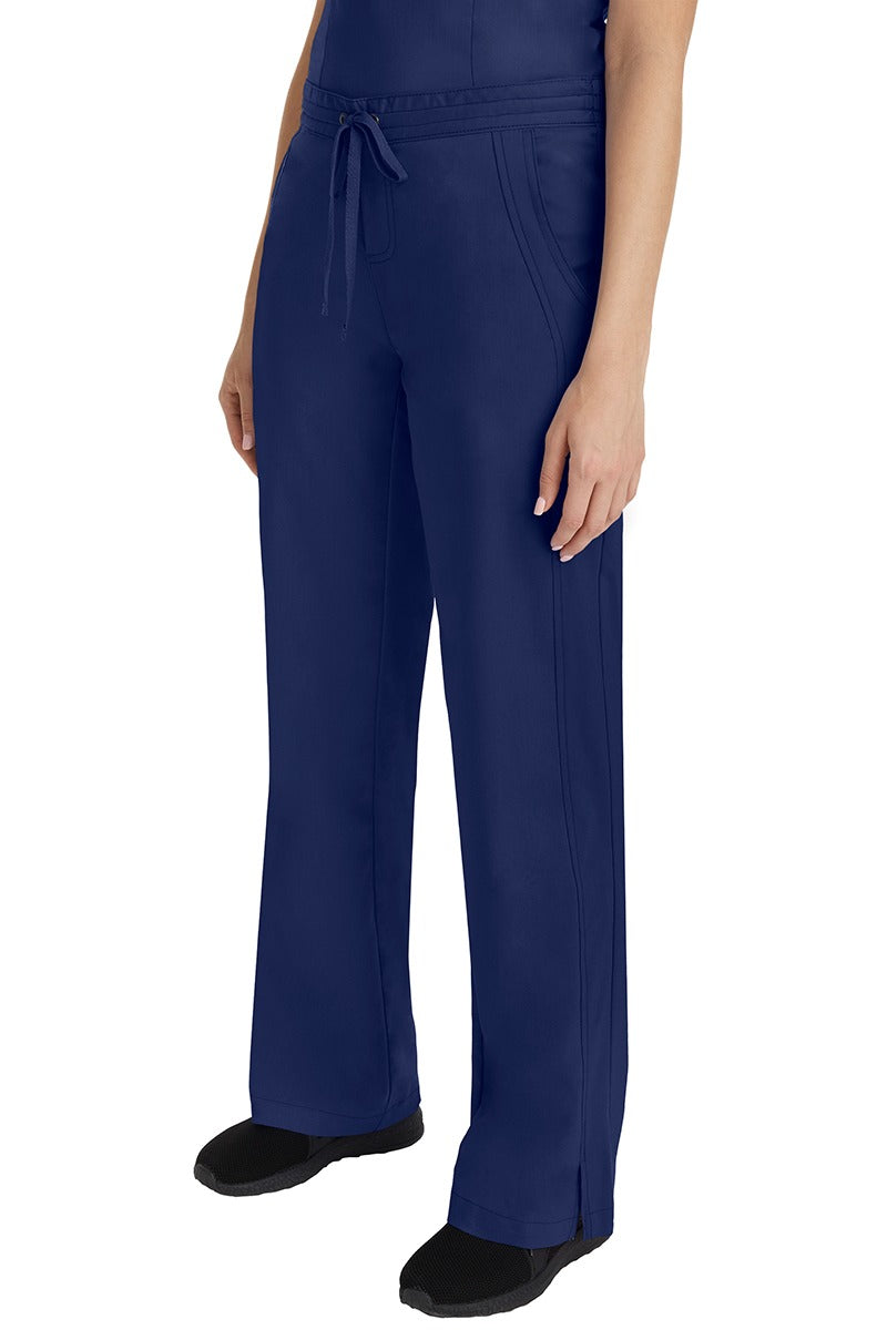 A young Home Care Registered Nurse wearing a Purple Label Women's Taylor Drawstring Scrub Pant in Navy featuring front wrap seaming detail throughout.