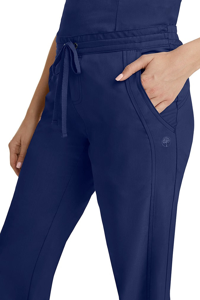 A young woman wearing a pair of Purple Label Women's Taylor Drawstring Scrub Pants from Healing Hands in Navy. Perfect for Healthcare Professionals working in Hospitals, Doctors offices, Dental Groups & Veterinary offices!