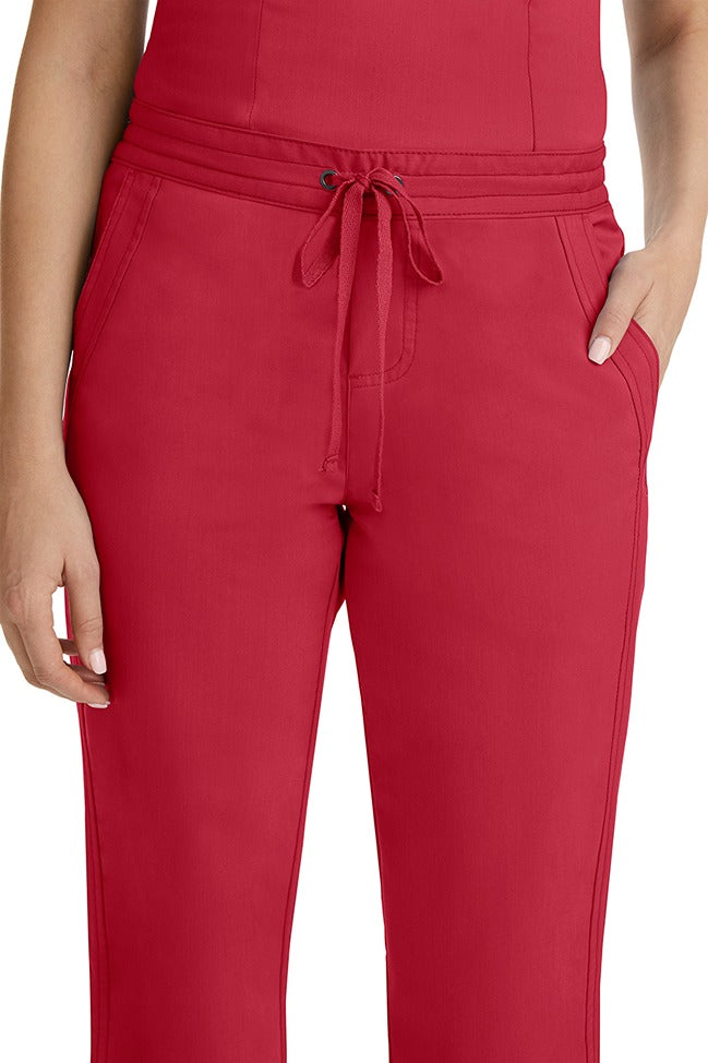 A female healthcare professional wearing a Purple Label Women's Taylor Drawstring Scrub Pant in Red featuring triple needle stitching throughout.