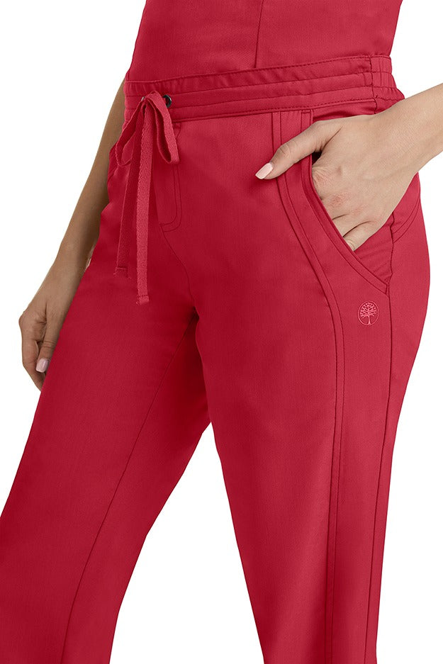 A young woman wearing a pair of Purple Label Women's Taylor Drawstring Scrub Pants from Healing Hands in Red. Perfect for Healthcare Professionals working in Hospitals, Doctors offices, Dental Groups & Veterinary offices!