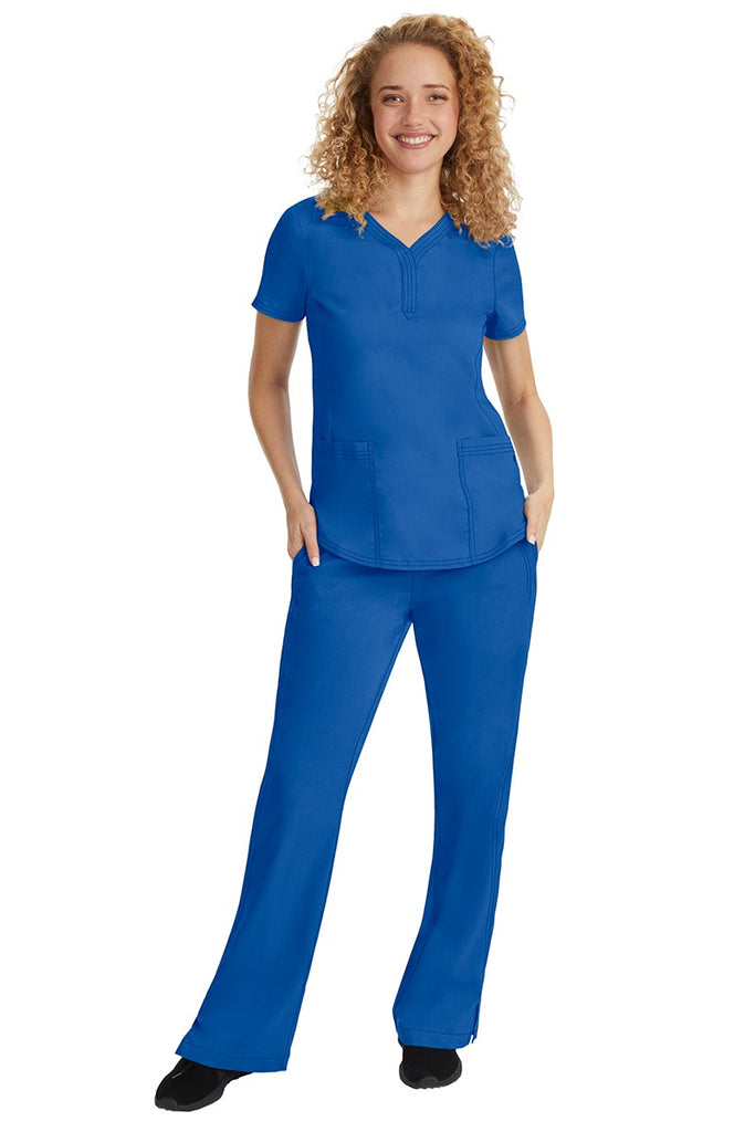 A young female nurse wearing a Purple Label Women's Taylor Drawstring Scrub Pant from Healing Hands in Royal featuring a fabric that resists wrinkles, shrinking & fading better than traditional cotton scrubs.