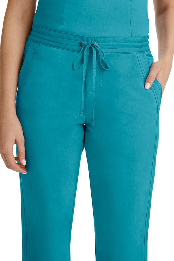 A female healthcare professional wearing a Purple Label Women's Taylor Drawstring Scrub Pant in Teal featuring triple needle stitching throughout.
