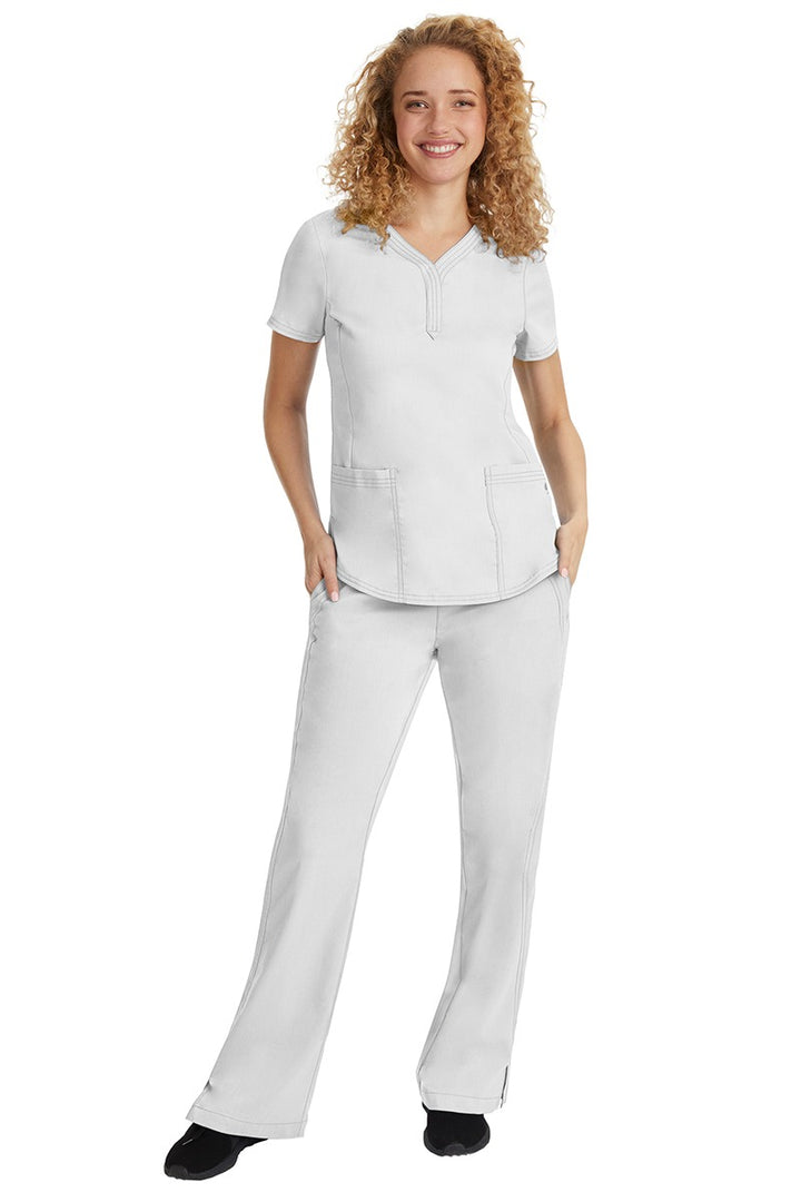 A young female nurse wearing a Purple Label Women's Taylor Drawstring Scrub Pant from Healing Hands in White featuring a fabric that resists wrinkles, shrinking & fading better than traditional cotton scrubs.