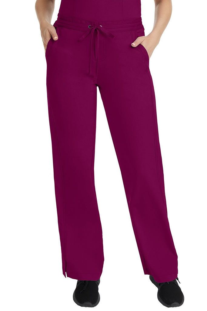 A female LPN wearing a pair of Purple Label Women's Taylor Drawstring Scrub Pants from Healing Hands in Wine featuring a front drawstring waist.