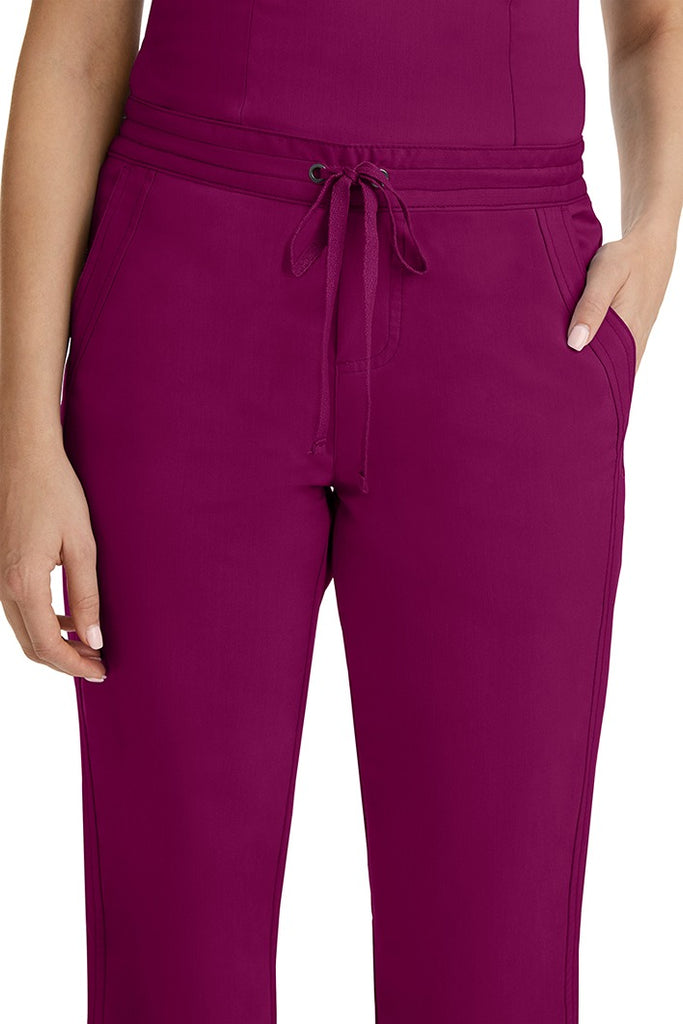 A female healthcare professional wearing a Purple Label Women's Taylor Drawstring Scrub Pant in Wine featuring triple needle stitching throughout.