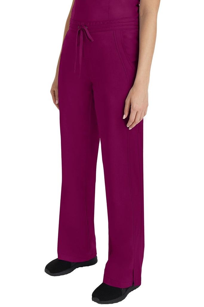A young Home Care Registered Nurse wearing a Purple Label Women's Taylor Drawstring Scrub Pant in Wine featuring front wrap seaming detail throughout.