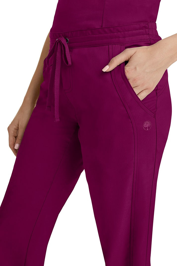 A young woman wearing a pair of Purple Label Women's Taylor Drawstring Scrub Pants from Healing Hands in Wine. Perfect for Healthcare Professionals working in Hospitals, Doctors offices, Dental Groups & Veterinary offices!