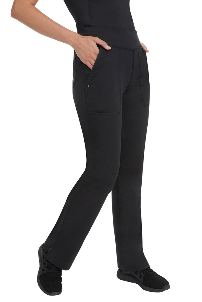 A young female LPN wearing a Purple Label Women's Tori Yoga Waistband Scrub Pant in Black featuring 2 front side-entry pockets with grommet details.