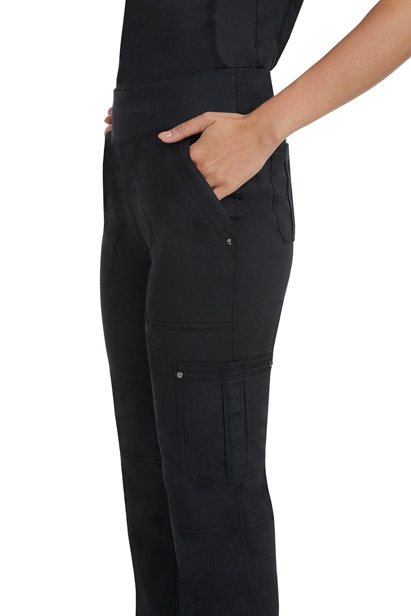 A young Home Care Registered Nurse wearing a pair of Purple Label Women's Tori Yoga Waistband Scrub Pants in Black featuring 1 outer cargo pocket on the wearer's left side pant leg. 
