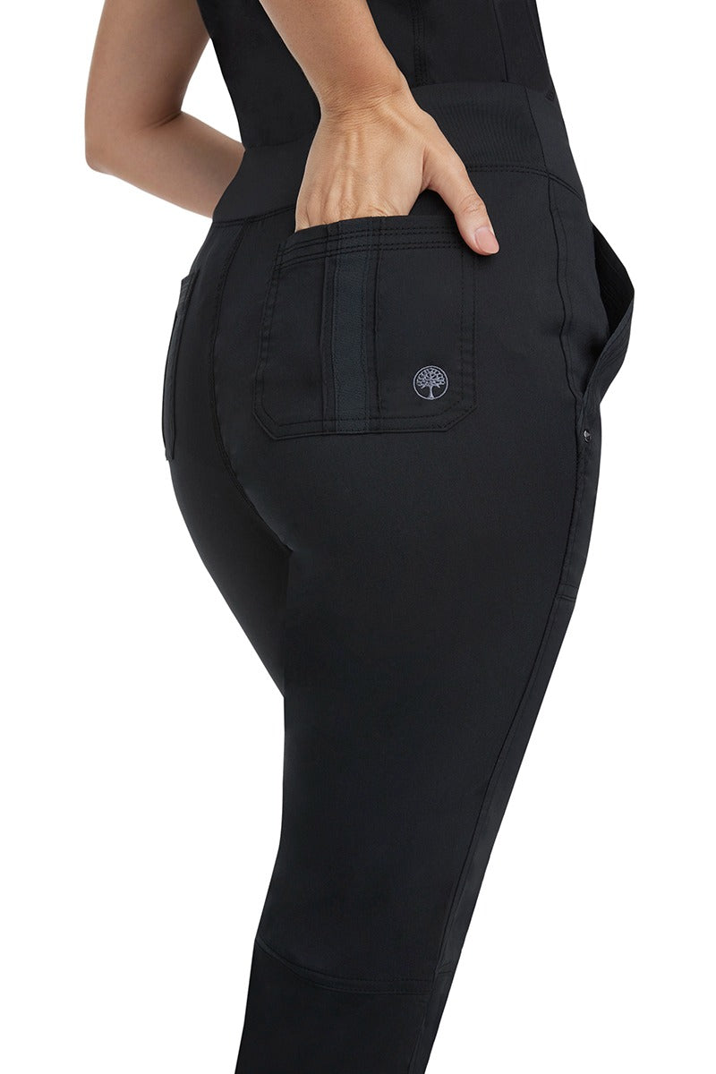 A young female healthcare professional wearing a Purple Label Women's Tori Yoga Waistband Scrub Pant in Black featuring a unique fabric that resists wrinkles, shrinking, & fading better than traditional cotton scrubs.
