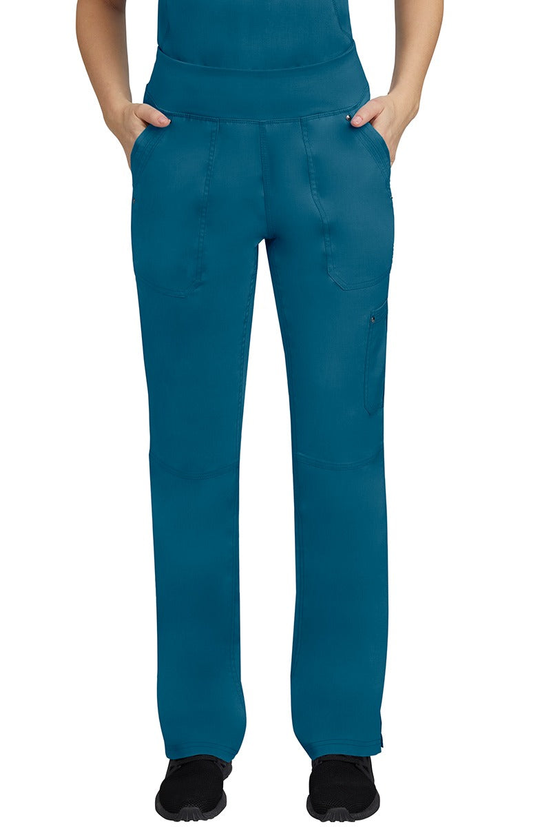 A young female LPN wearing a Purple Label Women's Tori Yoga Waistband Scrub Pant in Caribbean featuring 2 front side-entry pockets with grommet details.