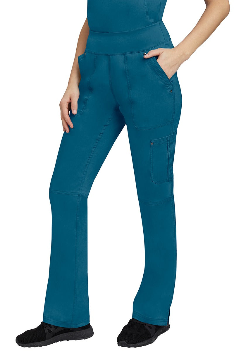 A young Home Care Registered Nurse wearing a pair of Purple Label Women's Tori Yoga Waistband Scrub Pants in Caribbean featuring 1 outer cargo pocket on the wearer's left side pant leg.