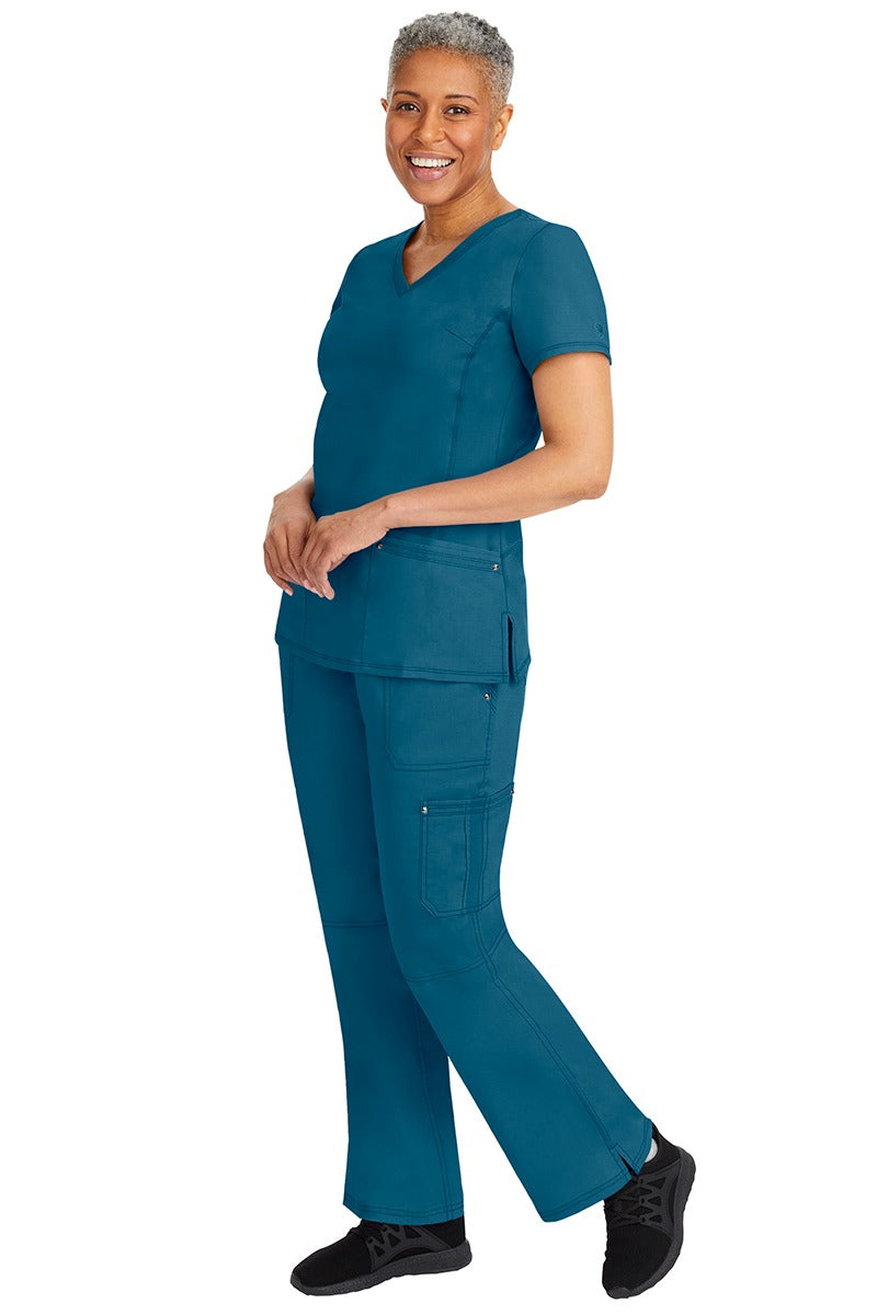 A young female nurse wearing a pair of Purple Label Women's Tori Yoga Waistband Scrub Pants from Healing Hands in Caribbean featuring a modern fit.
