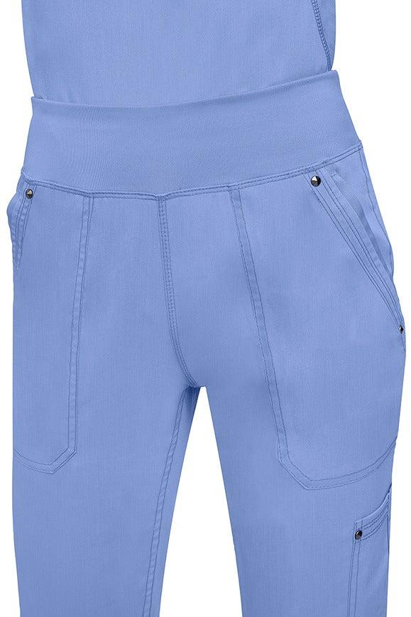 A young female healthcare professional wearing a Purple Label Women's Tori Yoga Waistband Scrub Pant in Ceil featuring a unique fabric that resists wrinkles, shrinking, & fading better than traditional cotton scrubs.
