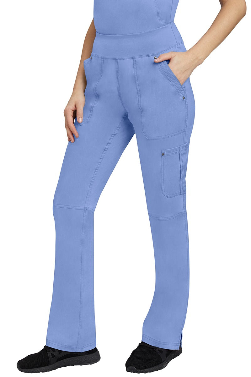 A young Home Care Registered Nurse wearing a pair of Purple Label Women's Tori Yoga Waistband Scrub Pants in Ceil featuring 1 outer cargo pocket on the wearer's left side pant leg.