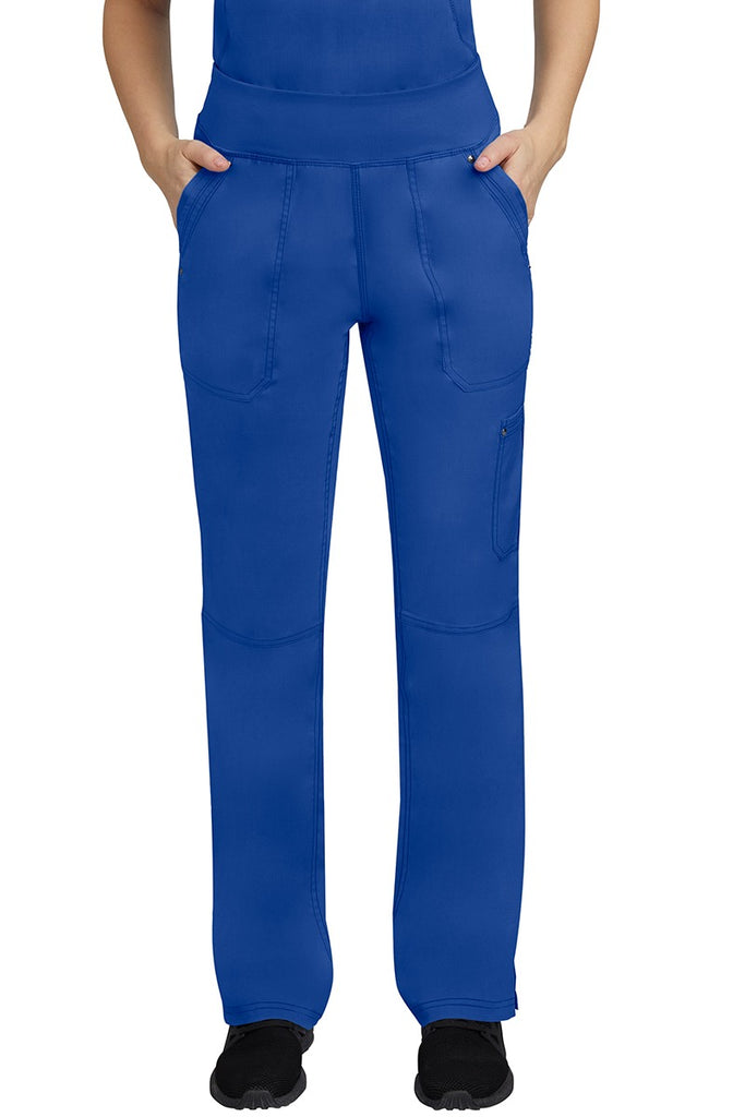 A young female LPN wearing a Purple Label Women's Tori Yoga Waistband Scrub Pant in Galaxy Blue featuring 2 front side-entry pockets with grommet details.