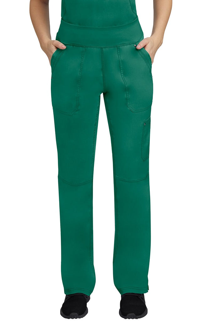 A young female LPN wearing a Purple Label Women's Tori Yoga Waistband Scrub Pant in Hunter Green featuring 2 front side-entry pockets with grommet details.