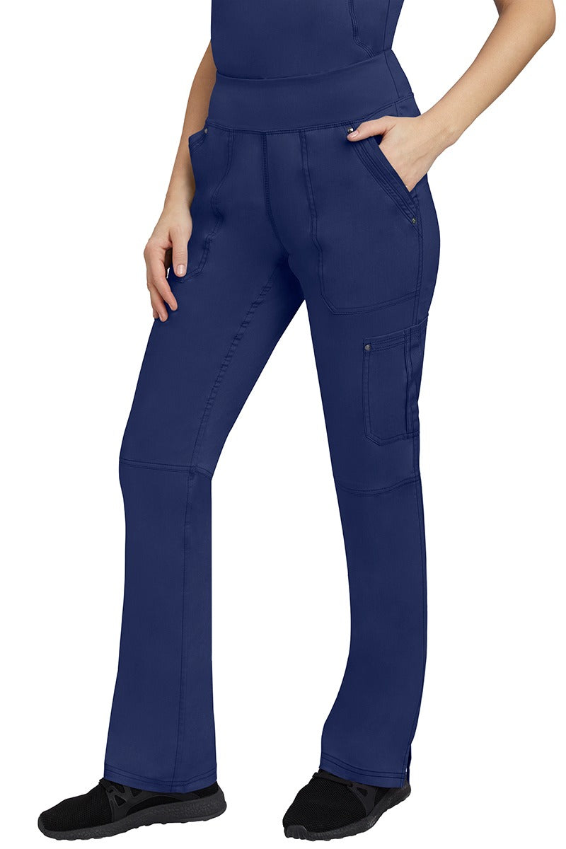 A young Home Care Registered Nurse wearing a pair of Purple Label Women's Tori Yoga Waistband Scrub Pants in Navy featuring 1 outer cargo pocket on the wearer's left side pant leg.