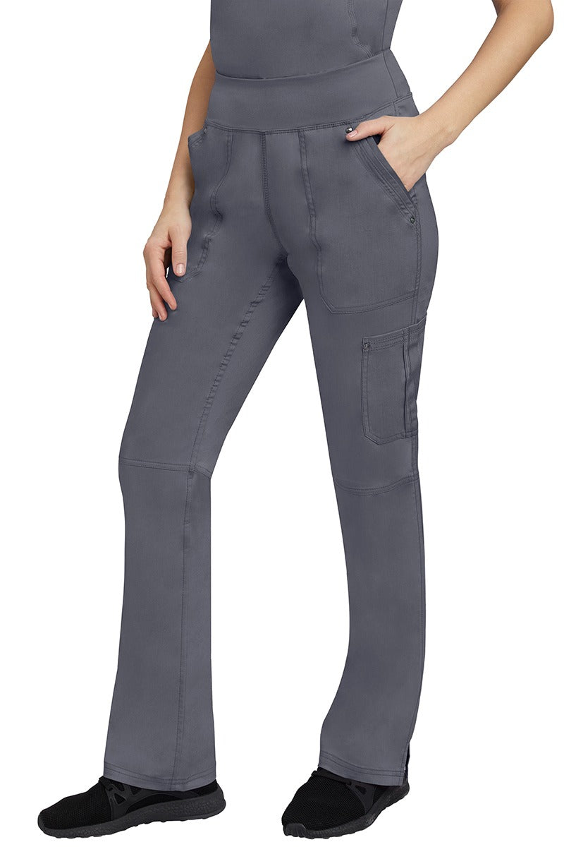 A young Home Care Registered Nurse wearing a pair of Purple Label Women's Tori Yoga Waistband Scrub Pants in Pewter featuring 1 outer cargo pocket on the wearer's left side pant leg.