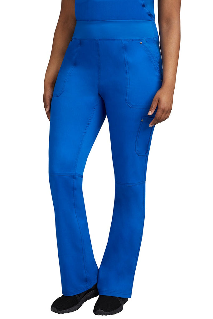 A young Home Care Registered Nurse wearing a pair of Purple Label Women's Tori Yoga Waistband Scrub Pants in Royal featuring 1 outer cargo pocket on the wearer's left side pant leg.