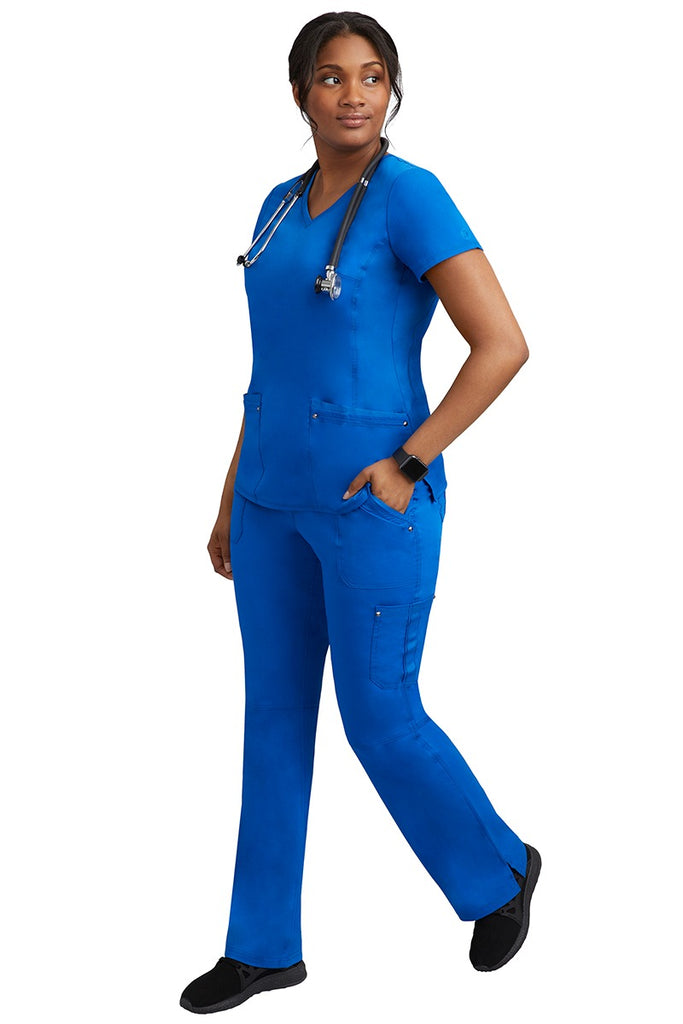 A young female nurse wearing a pair of Purple Label Women's Tori Yoga Waistband Scrub Pants from Healing Hands in Royal featuring a modern fit.