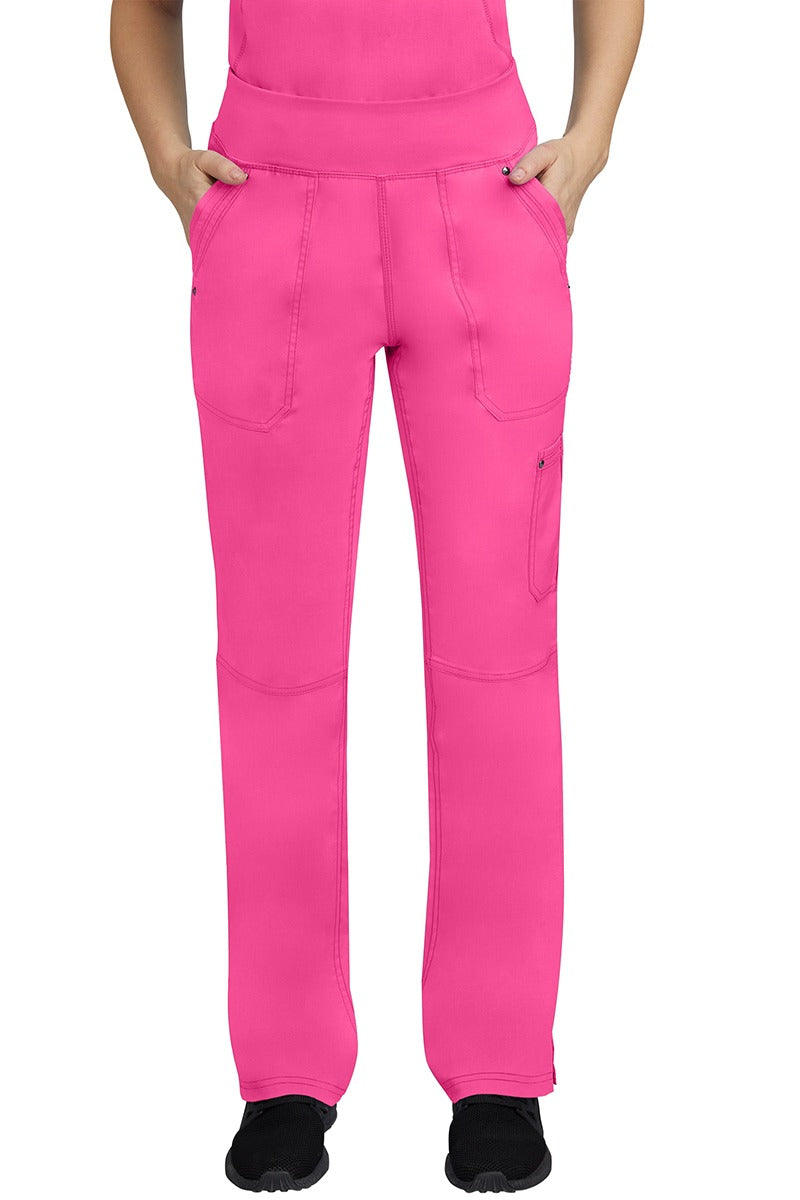 A young female LPN wearing a Purple Label Women's Tori Yoga Waistband Scrub Pant in Shocking Pink featuring 2 front side-entry pockets with grommet details.