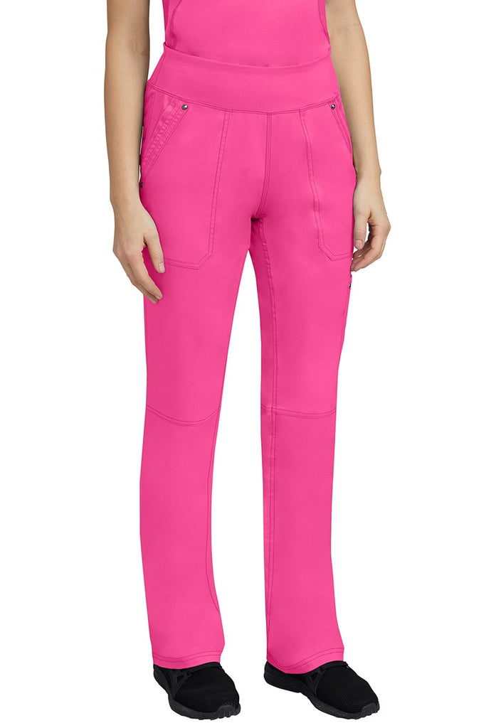 A young woman wearing a Purple Label Women's Tori Yoga Waistband Scrub Pant in Shocking Pink featuring a yoga knit waistband.