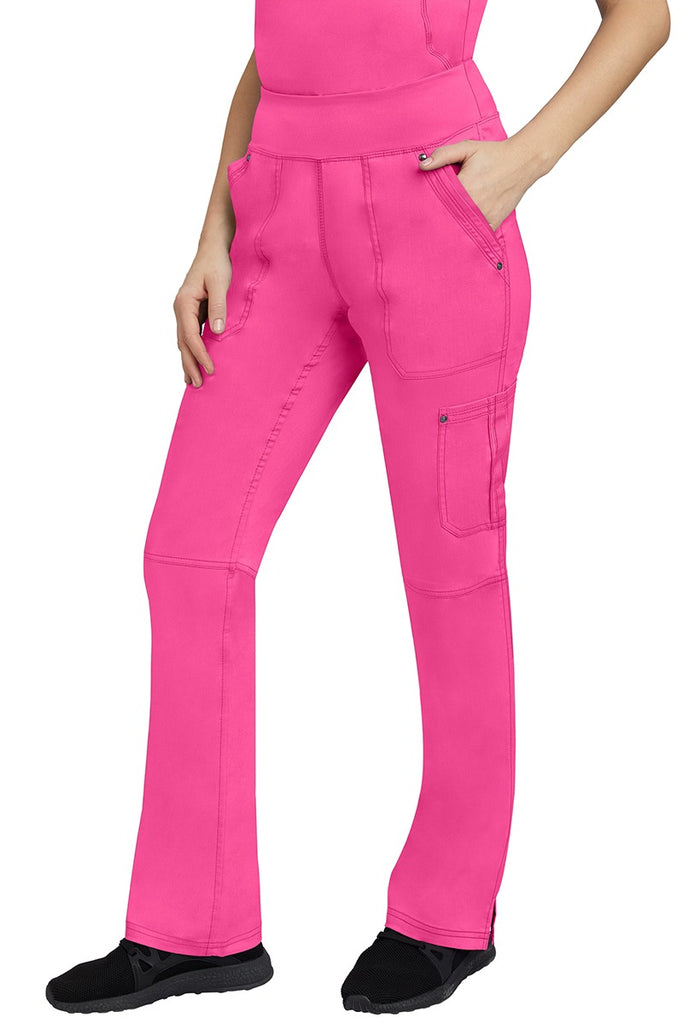 A young Home Care Registered Nurse wearing a pair of Purple Label Women's Tori Yoga Waistband Scrub Pants in Shocking Pink featuring 1 outer cargo pocket on the wearer's left side pant leg.